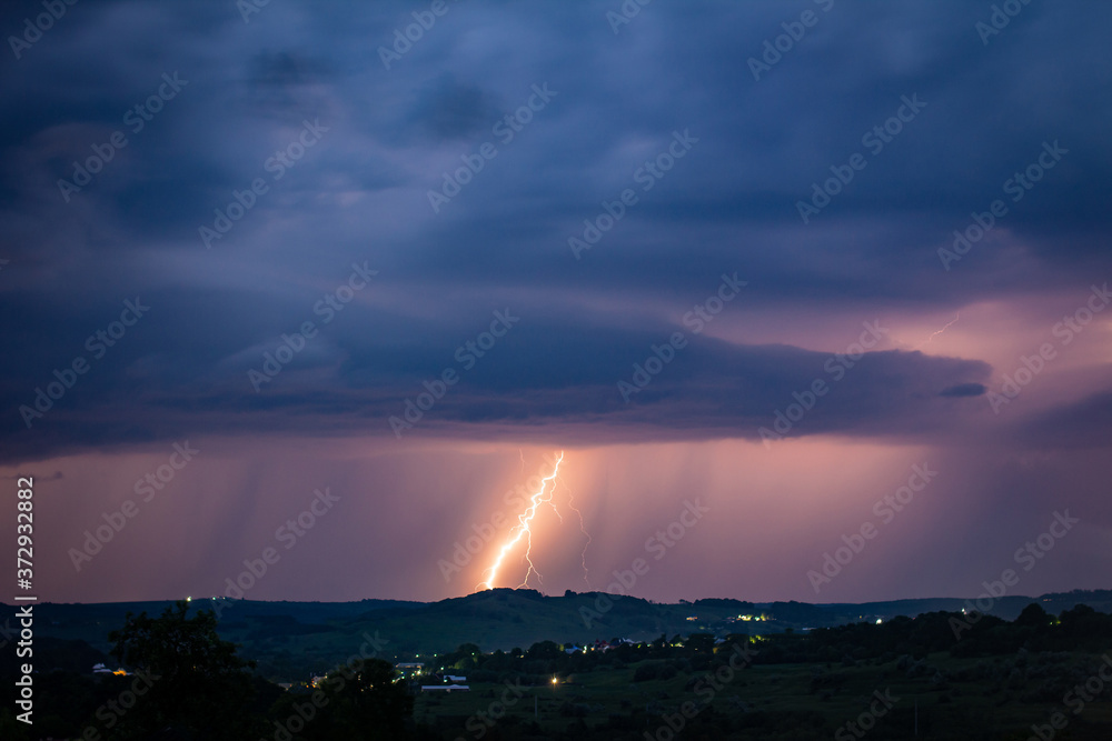 Night landscape on a background of thunderstorms. Rural silhouette and clouds with lightning flashes