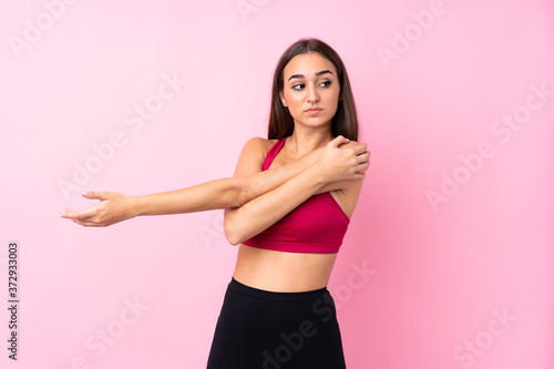 Young sport girl over isolated pink background stretching arm