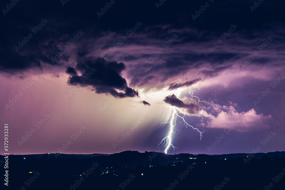 Night landscape on a background of thunderstorms. Rural silhouette and clouds with lightning flashes