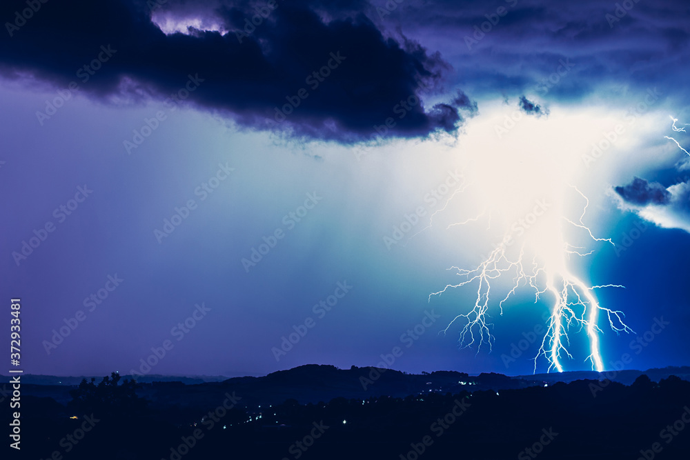 Night landscape on a background of thunderstorms. Rural silhouette and clouds with lightning flashes Night landscape on a background of thunderstorms. Rural silhouette and clouds with lightning flashes