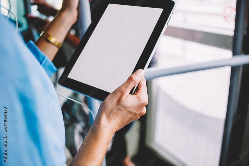 Close up view of woman's hands with tablet standing in tram and listening music from audi application installed on device.Female person holding modern touch pad with blank screen for internet message