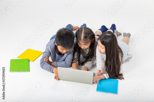 Three asian children lay on the floor and reading books over white background. photo