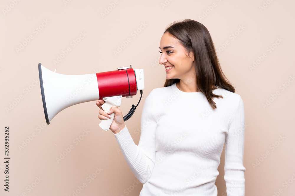 Young woman over isolated background shouting through a megaphone Young woman over isolated background shouting through a megaphone
