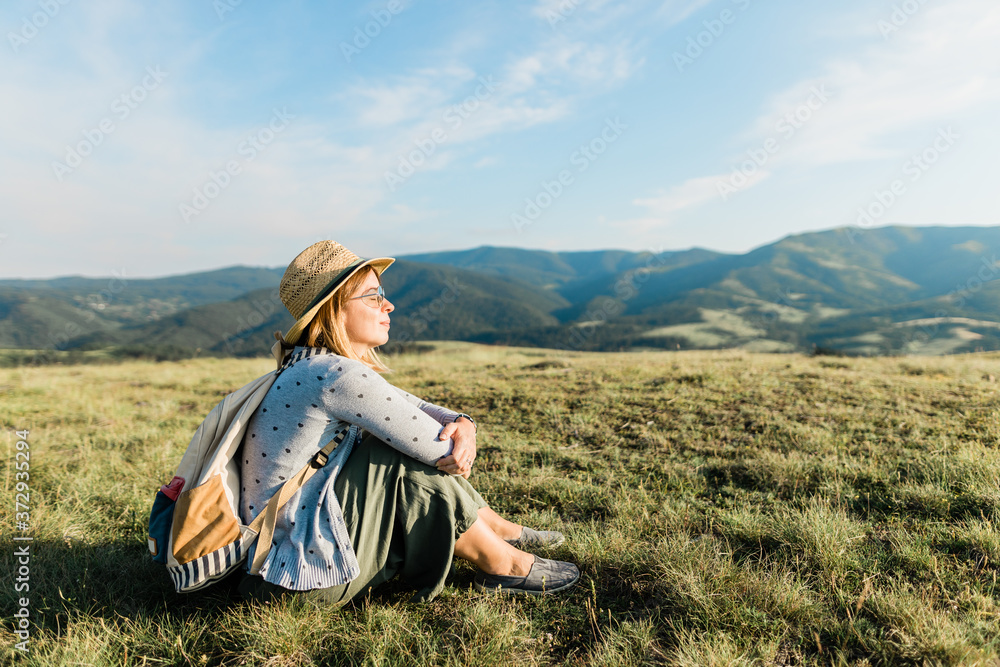 Young female nature lover enjoying the sunset in the mountains