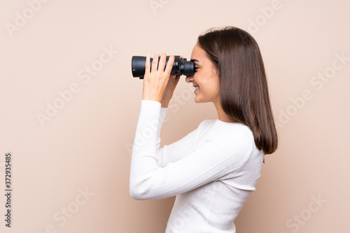 Young woman over isolated background with black binoculars © luismolinero