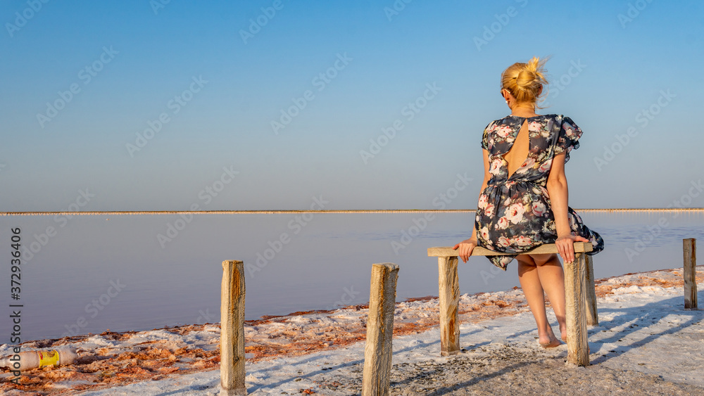 lady in a beautiful dress adult with a lovely smile on the background of a white lake of salt with blue clouds on a summer day