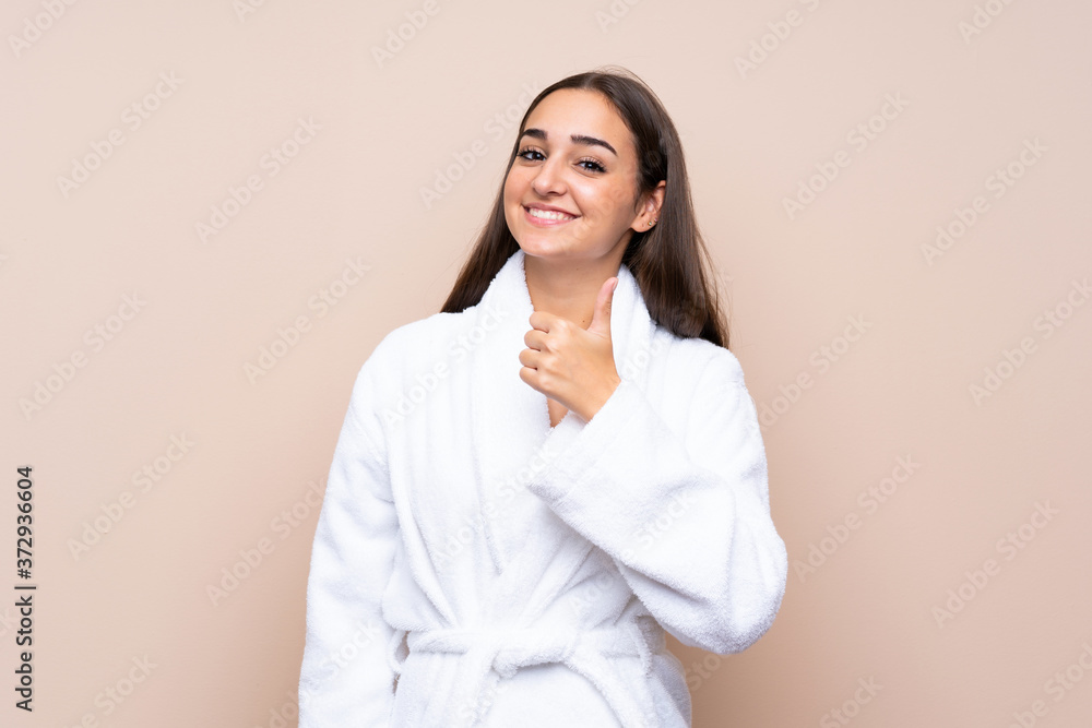 Young girl in a bathrobe over isolated background giving a thumbs up gesture Young girl in a bathrobe over isolated background giving a thumbs up gesture