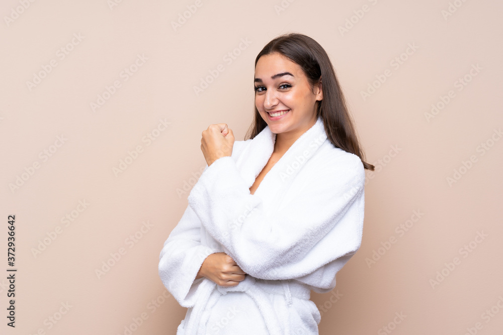 Young girl in a bathrobe over isolated background celebrating a victory Young girl in a bathrobe over isolated background celebrating a victory