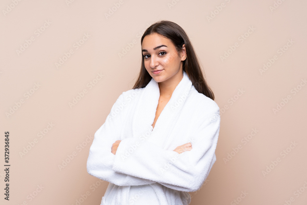 Young girl in a bathrobe over isolated background keeping arms crossed Young girl in a bathrobe over isolated background keeping arms crossed