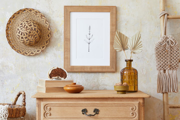 Stylish boho interior of living room with brown mock up poster frame, elegant accessories, flowers in vase, wooden shelf and hanging rattan hut. Minimalistic concept of home decor. Template.