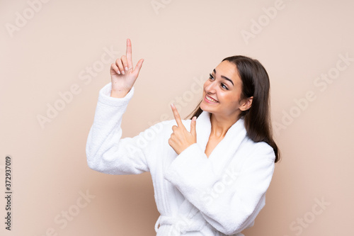 Young girl in a bathrobe over isolated background pointing with the index finger a great idea