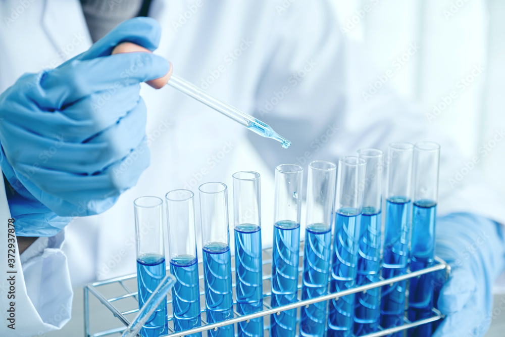 Scientists hold the pipette and drop the blue chemical liquid for research and analysis in a laboratory Scientists hold the pipette and drop the blue chemical liquid for research and analysis in a laboratory