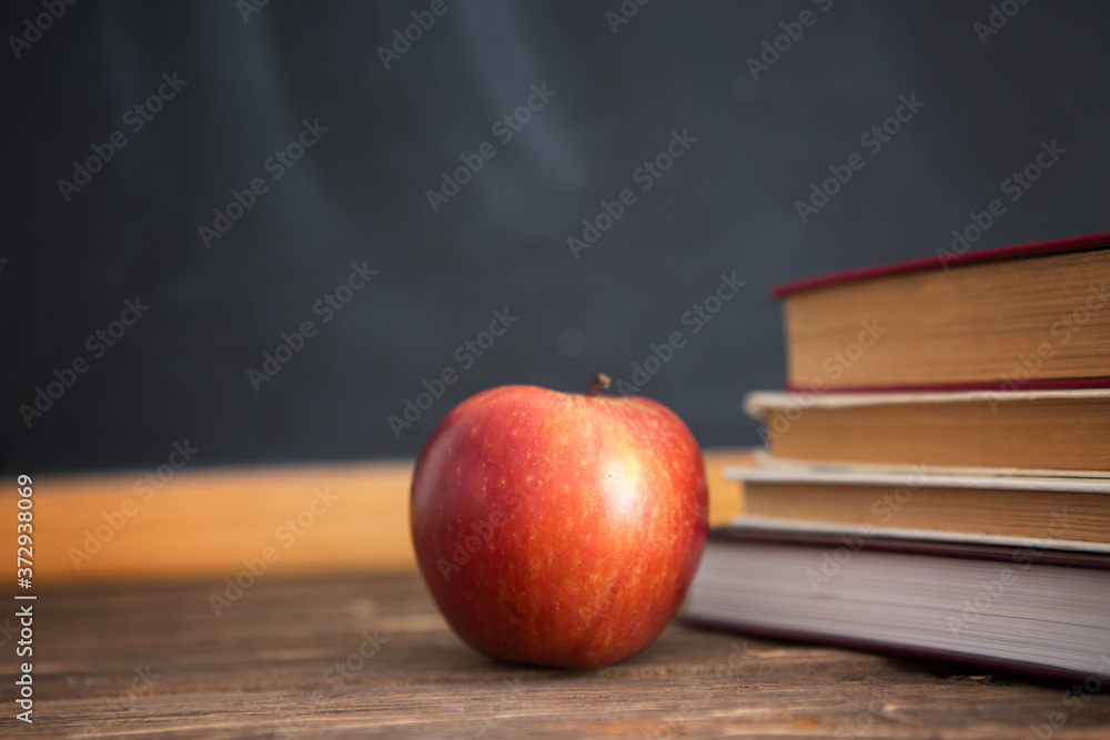 Books and apples on wooden table against the background of the chalkboard or blackboard. Books and apples on wooden table against the background of the chalkboard or blackboard.