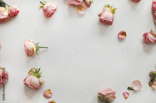Floral composition with frame of pink rose flowers on white background. Flat lay, top view mockup, copy space template
