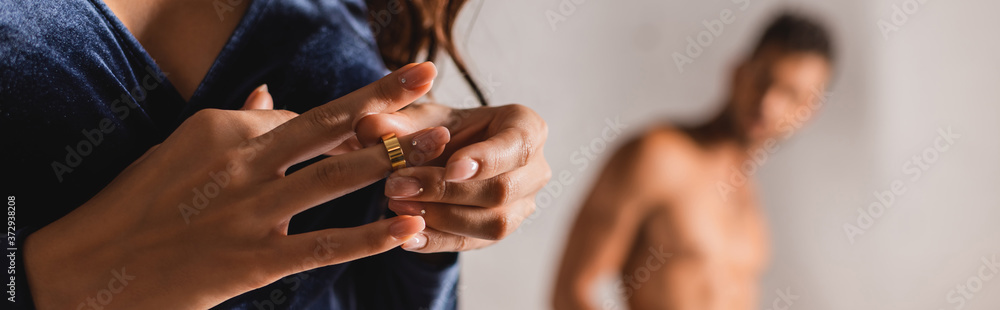 Panoramic orientation of woman taking off wedding ring with shirtless man at background