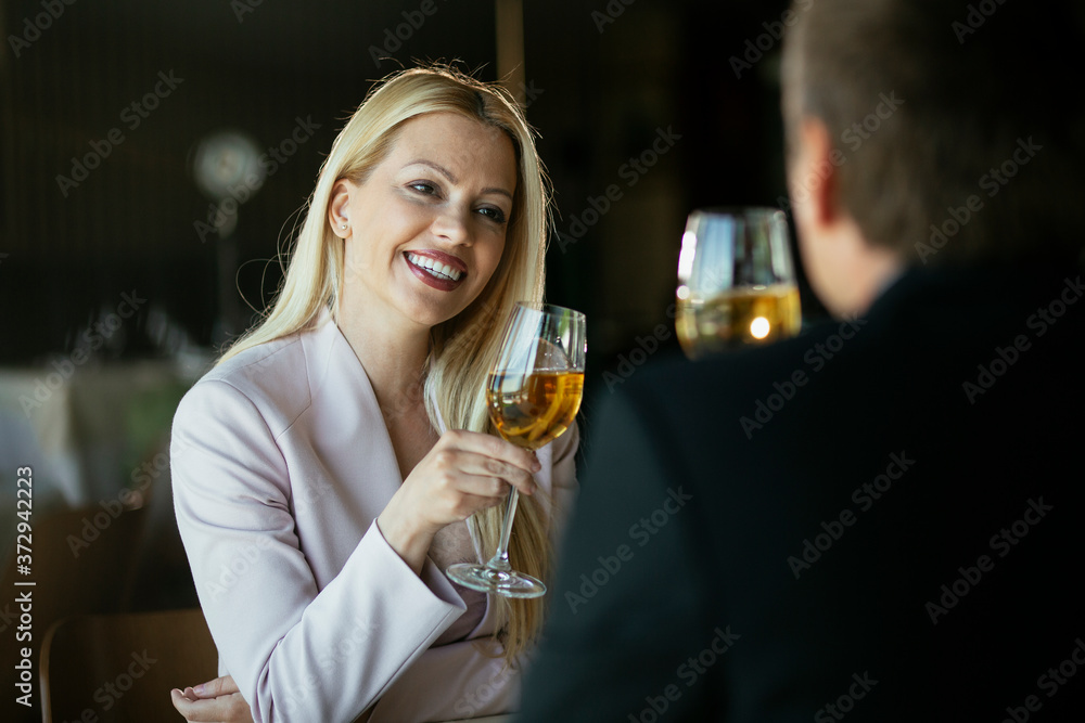 Beautiful businesswoman dressed in the suit drinking wine. Businessman and businesswoman enjoying in the restaurant.