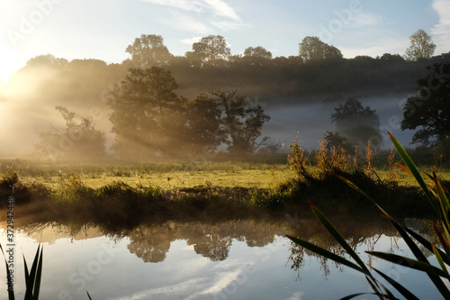 Early morning mist over the meadows on the River Wey in Godalming, Surrey, on a cold autumn morning.
