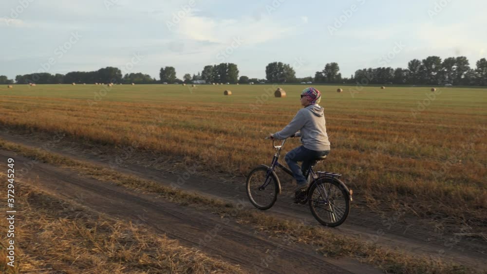 Bicycle. A bicyclist girl in a headscarf rides a Bicycle on a rural road full of twisted straw bales in a field. Bicycle. A bicyclist girl in a headscarf rides a Bicycle on a rural road full of twisted straw bales in a field.