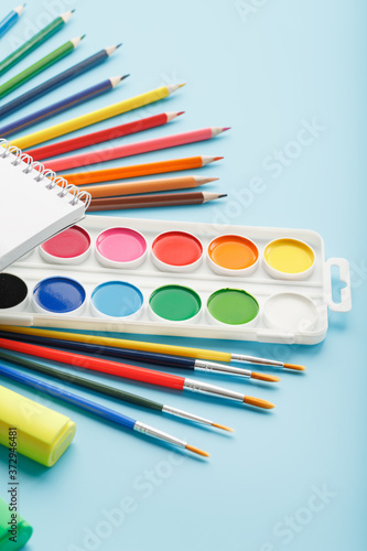 An album for drawing and creativity for school with stationery, a palette of colored paints, markers, brushes and pencils.