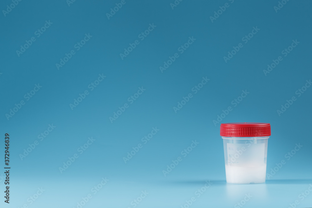 Semen in a test container with a red lid on a blue background.