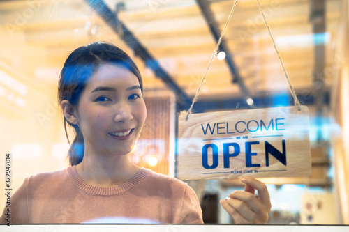 Small business, An Asian woman who owns a business opens the store and smiles to welcome customers.