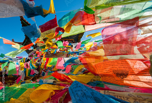 Colorful Tibetan Buddhist prayer flags hanging from a pagoda near Kawa Garpo mountains, home of one of Tibetan Buddhism's most sacred pilgrimages. 