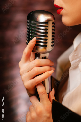 Singer lips and retro microphone. Girl on stage holding a microphone close up. Sensual performance of the song.