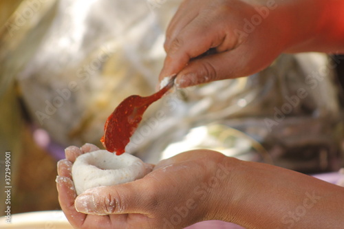 Obraz na płótnie hands of indigenous woman adding red sauce to make Mexican tamales called corundas
w salonie