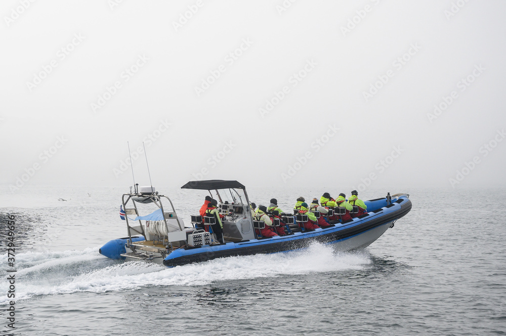 Tourists on speedboat during starting whale watching tour in foggy weather conditions Tourists on speedboat during starting whale watching tour in foggy weather conditions