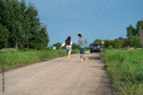 Brother and sister walking together. Happy couple walking along the road. Girl and guy walking countryside. Healthy lifestyle concept.