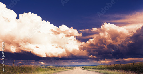 A dramatic summer storm forms above a gravel township road in Rocky View County Alberta