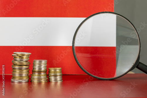 Magnifying glass and coins in front of Austria flag, country economy concept