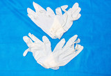 White medical gloves on a blue textured background.