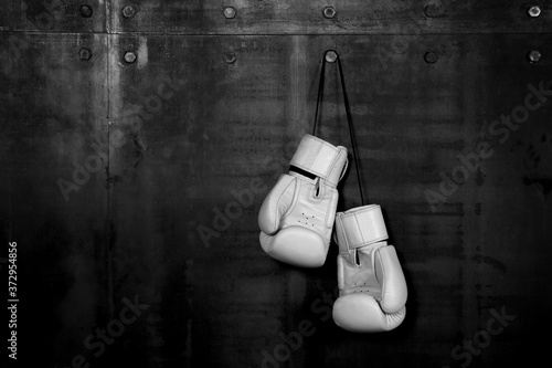 White leather boxing gloves hanging on black wall © breakingthewalls