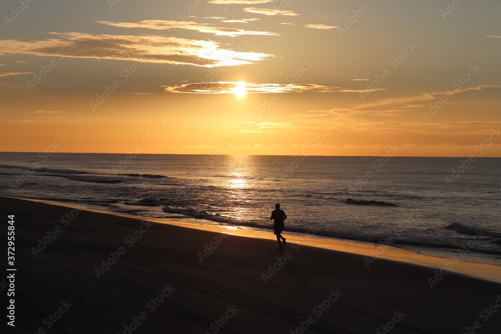 silhouette of a man jogging  on the beach