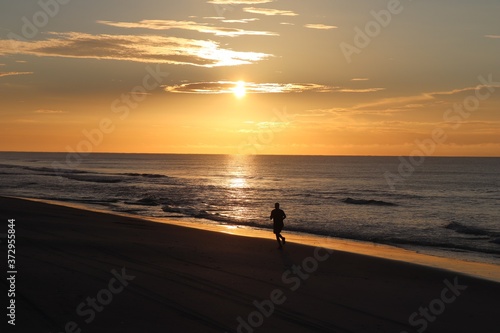 silhouette of a man jogging  on the beach © Fillmore