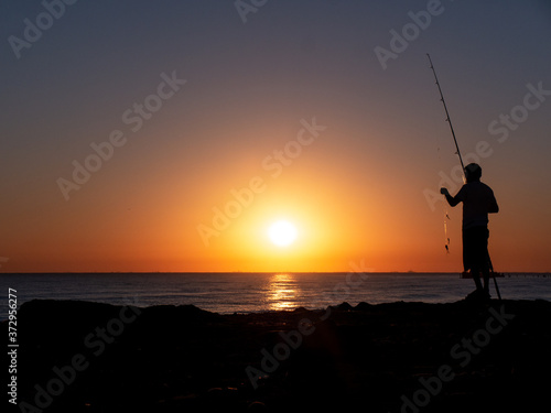 silhouette of fisherman by the ocean in sunrise, A fisherman in sunset at the coast 