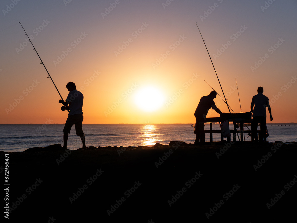 silhouette of fisherman by the ocean in sunrise, A fisherman in sunset at the coast
