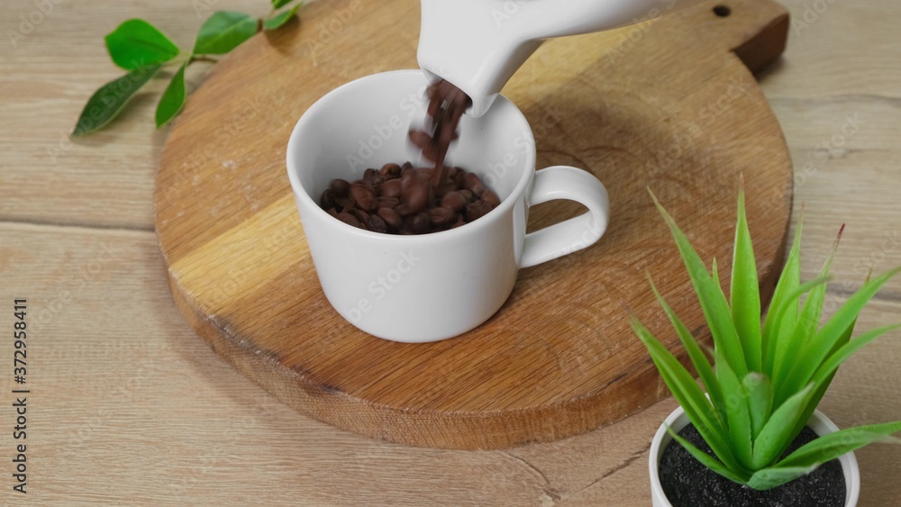 Coffee beans is poured into a cup from pot. Coffee beans is poured into a cup from pot.