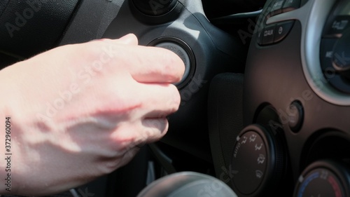 Male hand inserting car key into lock and starting engine close-up
