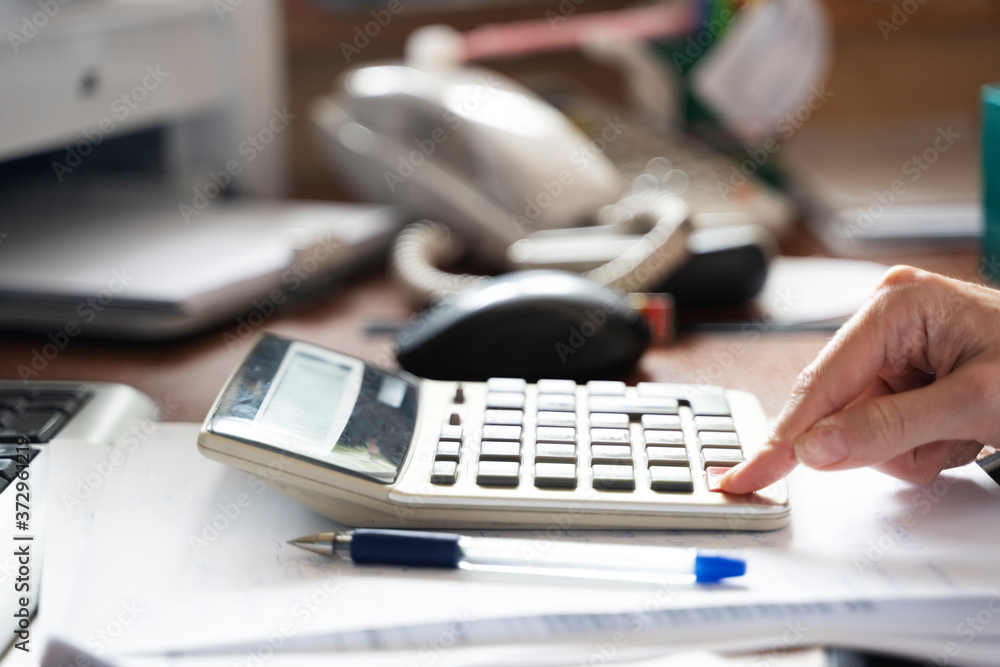 Fototapeta premium Girl at the Desk counts on a calculator, business concept