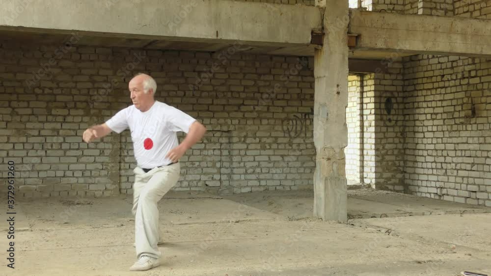 An old athlete in a white t-shirt trains blocks and punches An old athlete in a white t-shirt trains blocks and punches