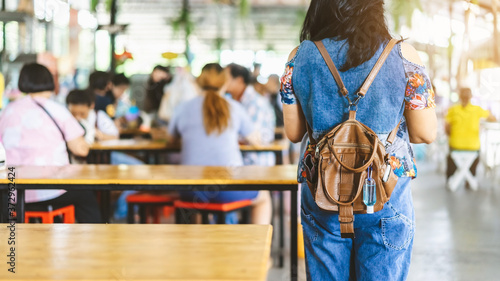 Mini portable alcohol gel bottle to kill Corona Virus(Covid-19) hang on a leather shoulder bag of a woman wear a protective mask at a cafeteria. New normal lifestyle. Selective focus on alcohol gel