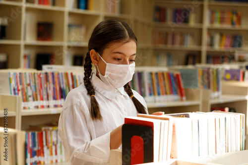 student working in the library with a face mask.