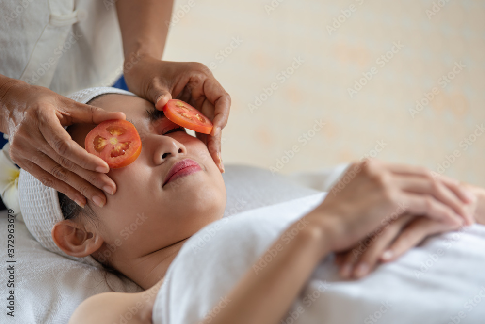 Beautiful Asian woman relax and lying on massage bed with fresh tomatoes mask in spa salon Beautiful Asian woman relax and lying on massage bed with fresh tomatoes mask in spa salon