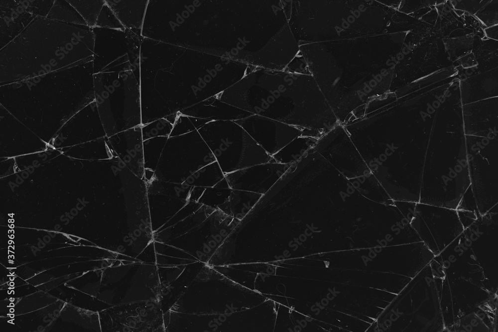 Black cracked glass texture background. Crack on the glass. Broken screen. Broken dark phone.  White cracks in glass