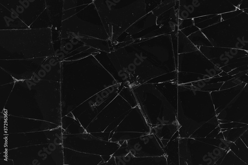 Black cracked glass texture background. Crack on the glass. Broken screen. Broken dark phone. White cracks in glass