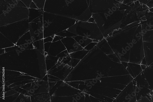 Black cracked glass texture background. Crack on the glass. Broken screen. Broken dark phone.  White cracks in glass