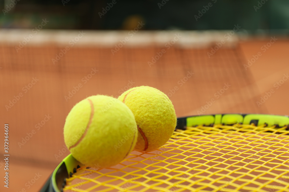 Tennis racquet with tennis balls against clay court