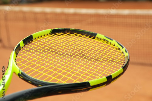 Tennis racquet against clay court, close up © Atlas